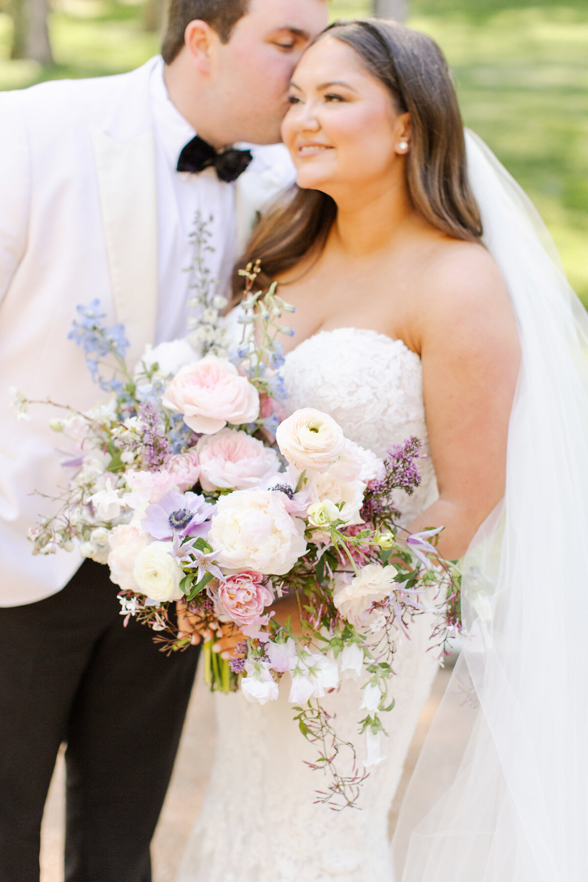 Elegant bridal bouquet in soft pastel colors, including shades of pink, white, and lavender. Mix of roses, peonies, and other delicate blooms, accented with greenery. Lush garden style bridal bouquet for spring wedding. Bridesmaids’ bouquets accenting bridal. Design by Rosemary & Finch Floral Design in Nashville, TN. 
