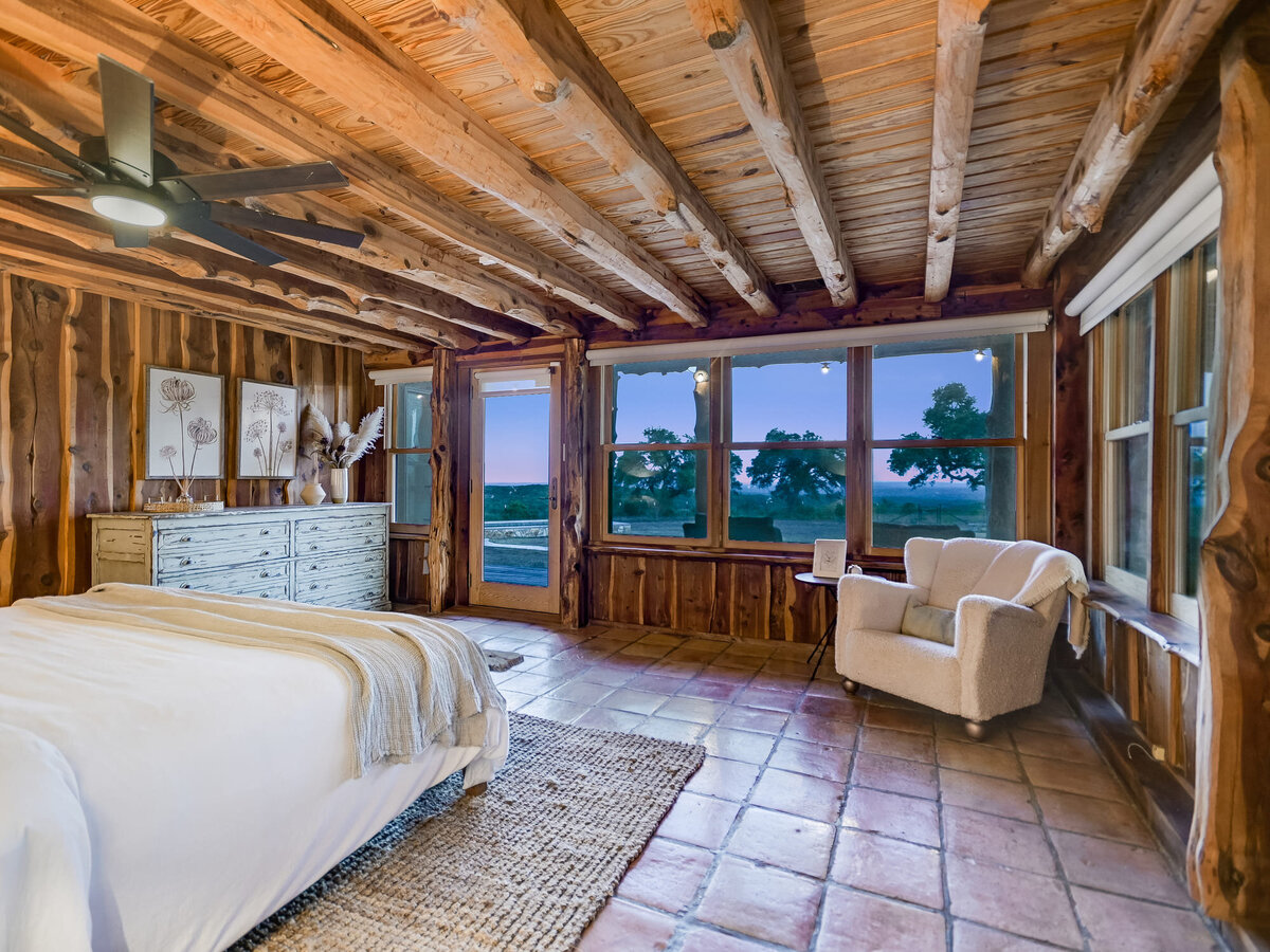 Large main double bedroom with wooden ceilings and single arm chair