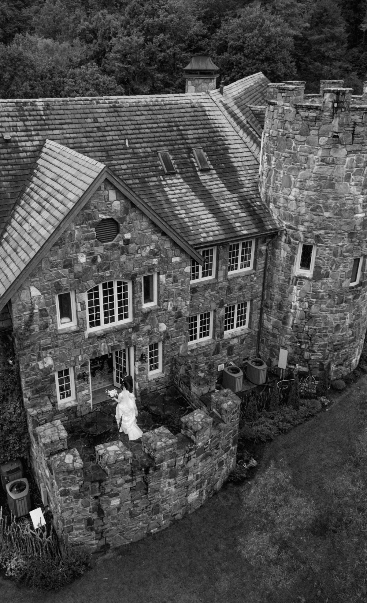 Black and white image of the bride and groom standing on the stone balcony of Castle Ladyhawke during her fall wedding.

