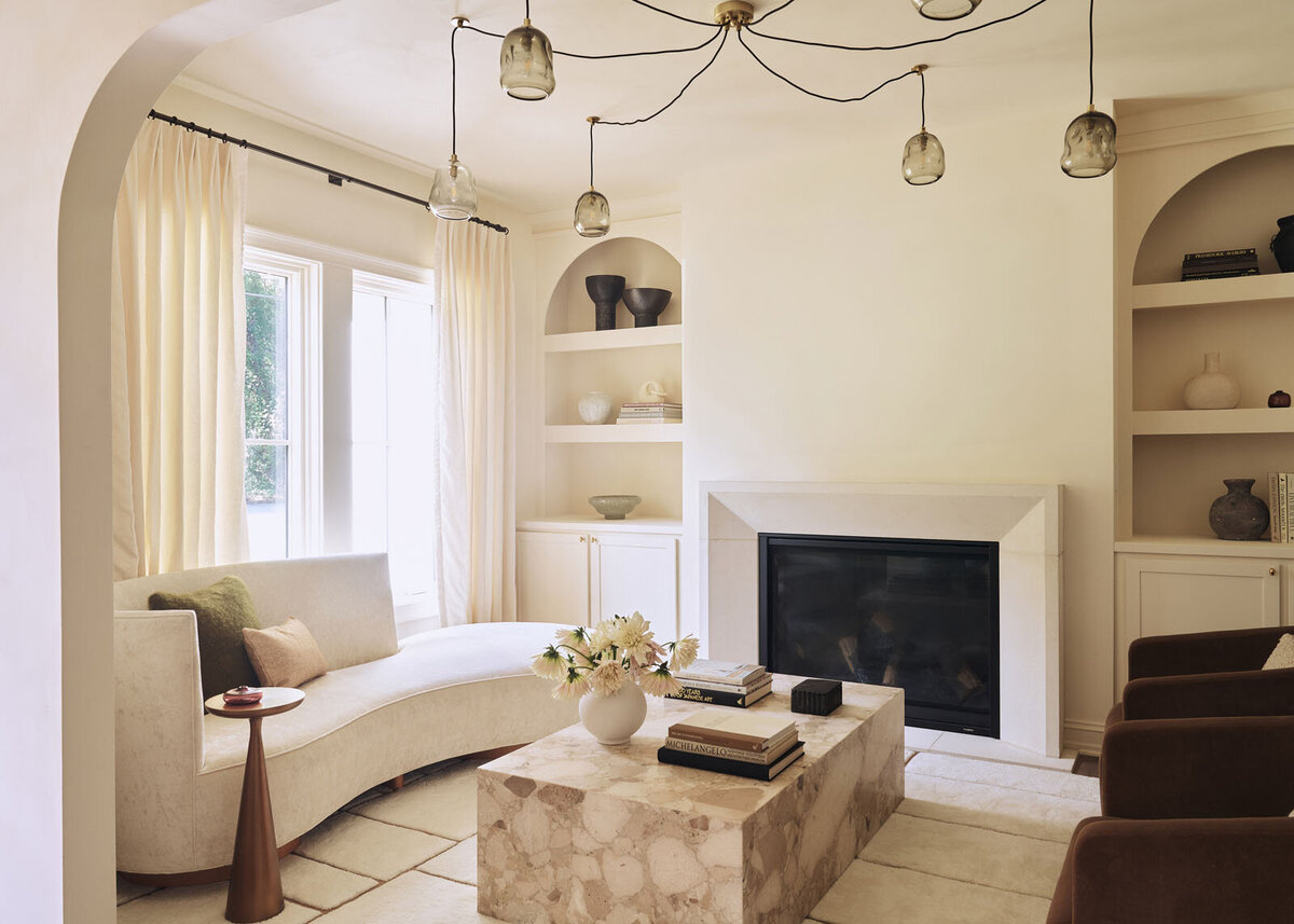Bold living room with beige couches, green velvet ottoman and patterned artwork