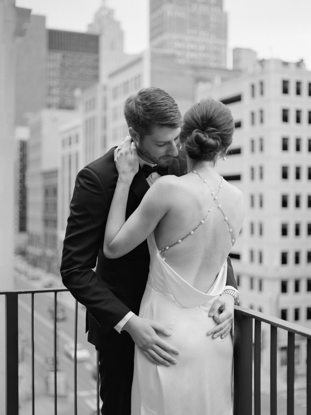 couple embraces, bride in backless open back wedding dress, pearl detail