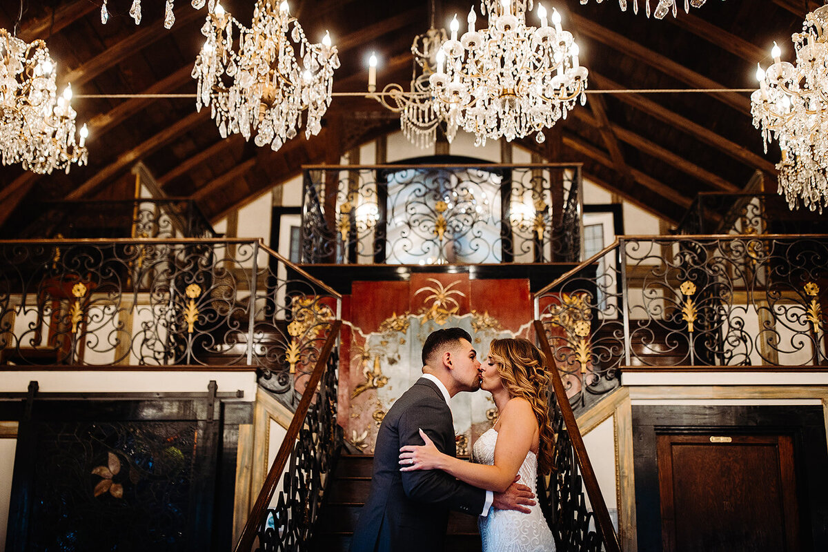 Bride and groom share a kiss in the chandelier barn at Lionsgate Event Venue in Lafayette, Colorado.
