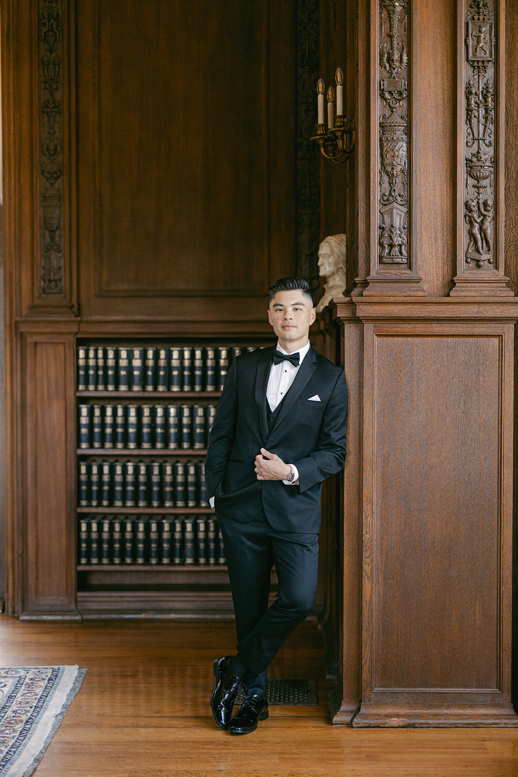Groom stands for portrait in the library of Kohl Mansion in San Francisco.