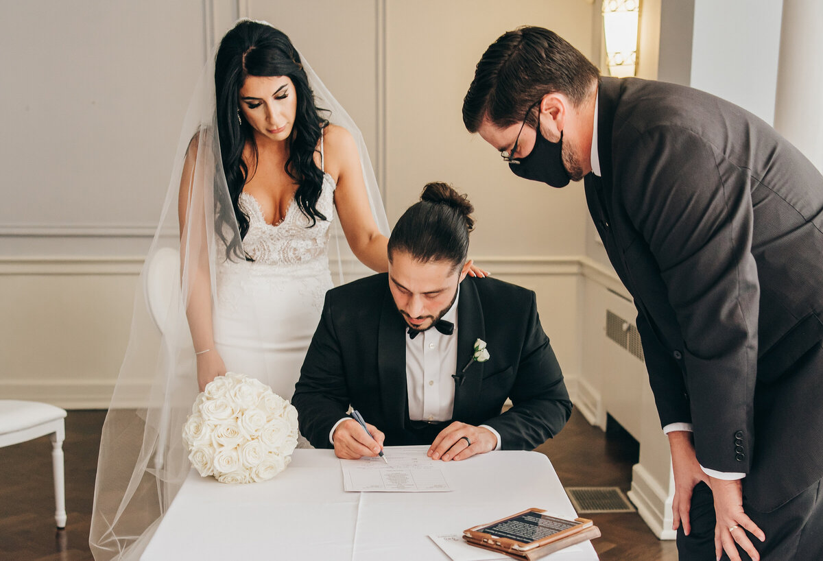 Bride and groom signing the registry at their black tie wedding ceremony