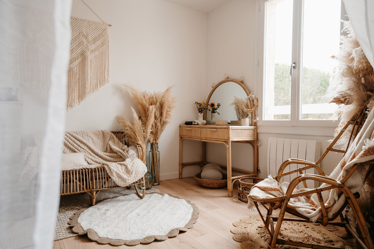 Studio photo en Vendée de Laura, photographe professionnelle. Décoré de fauteuils en rotin, pampas, plaid, tapis, coiffeuse pour une ambiance cosy et chaleureuse.