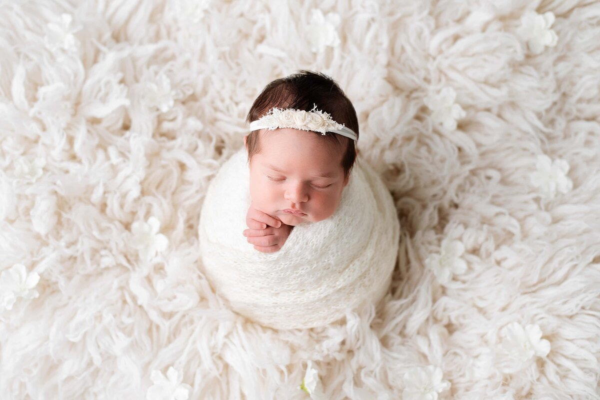 White potato flokati wrap with newborn girl surrounded by flowers