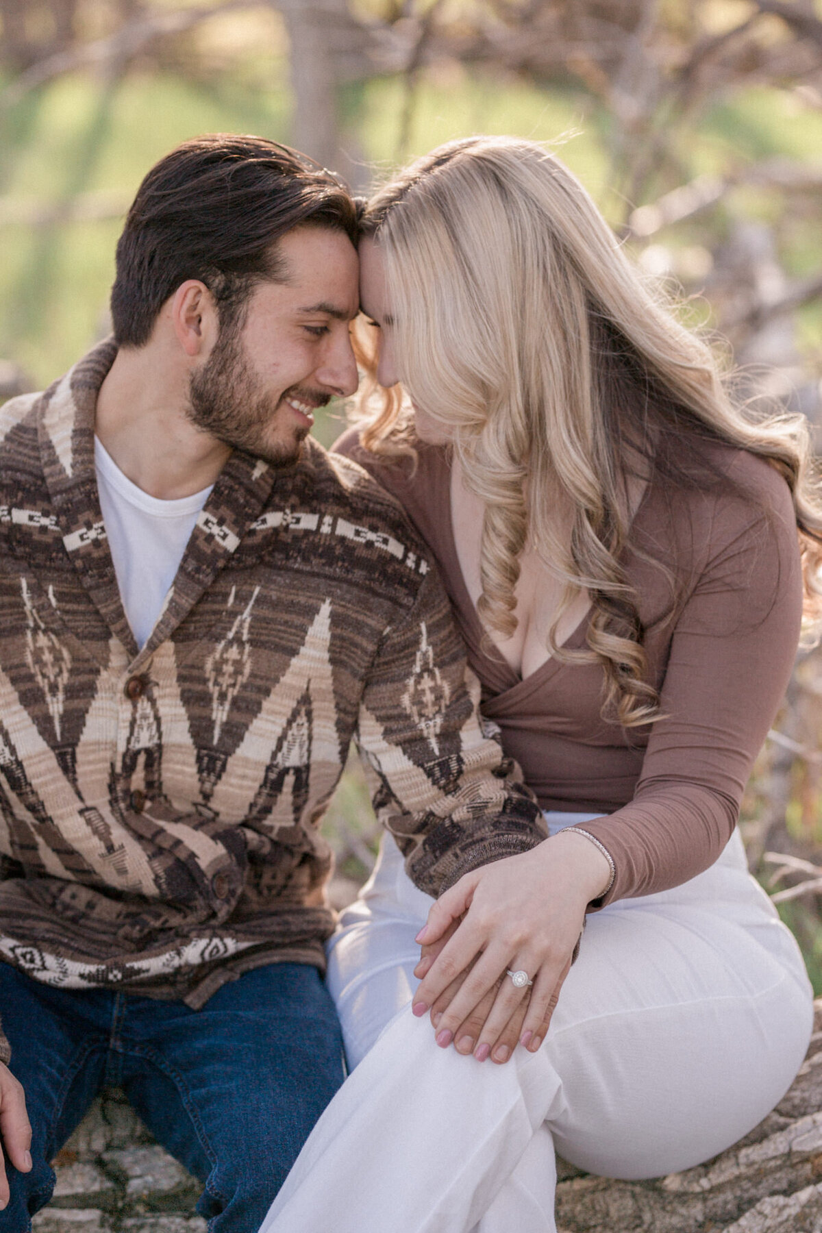 A couple touch their foreheads together while seated on a fallen tree. Boulder Engagement Photography by Stephanie Eddy