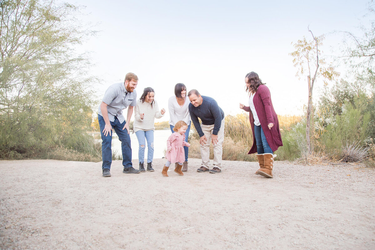 Familyl dancing with toddler in pink dress by a desert pond
