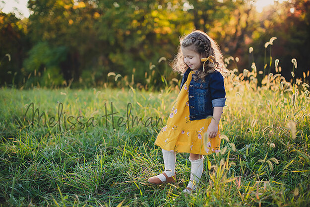 little girl walking in grass field