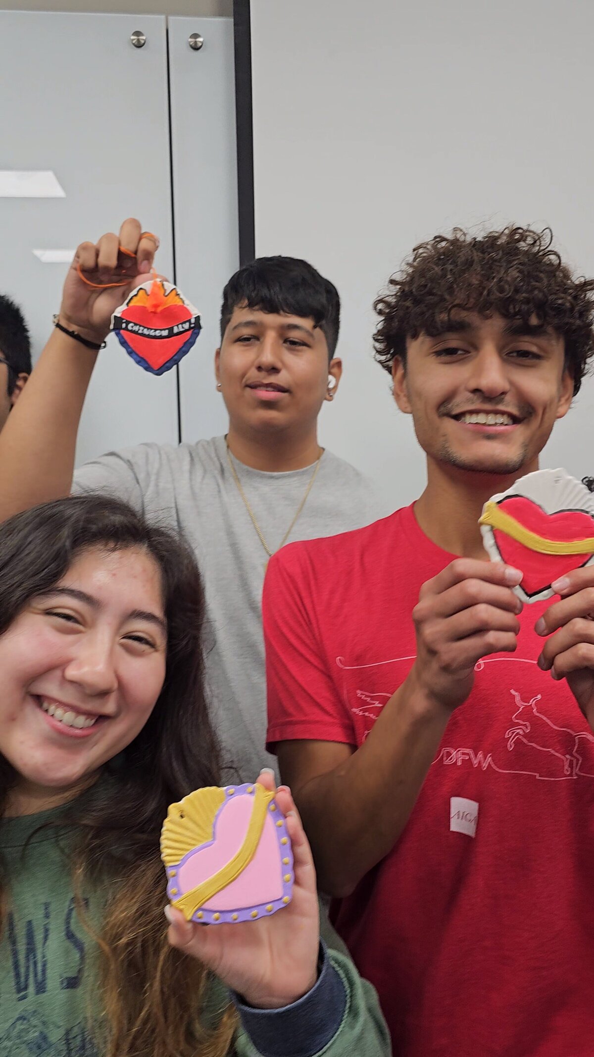 The vibrancy of youth expressing their creativity as three young individuals proudly display the handcrafted hearts they made in Ursula's art workshops.