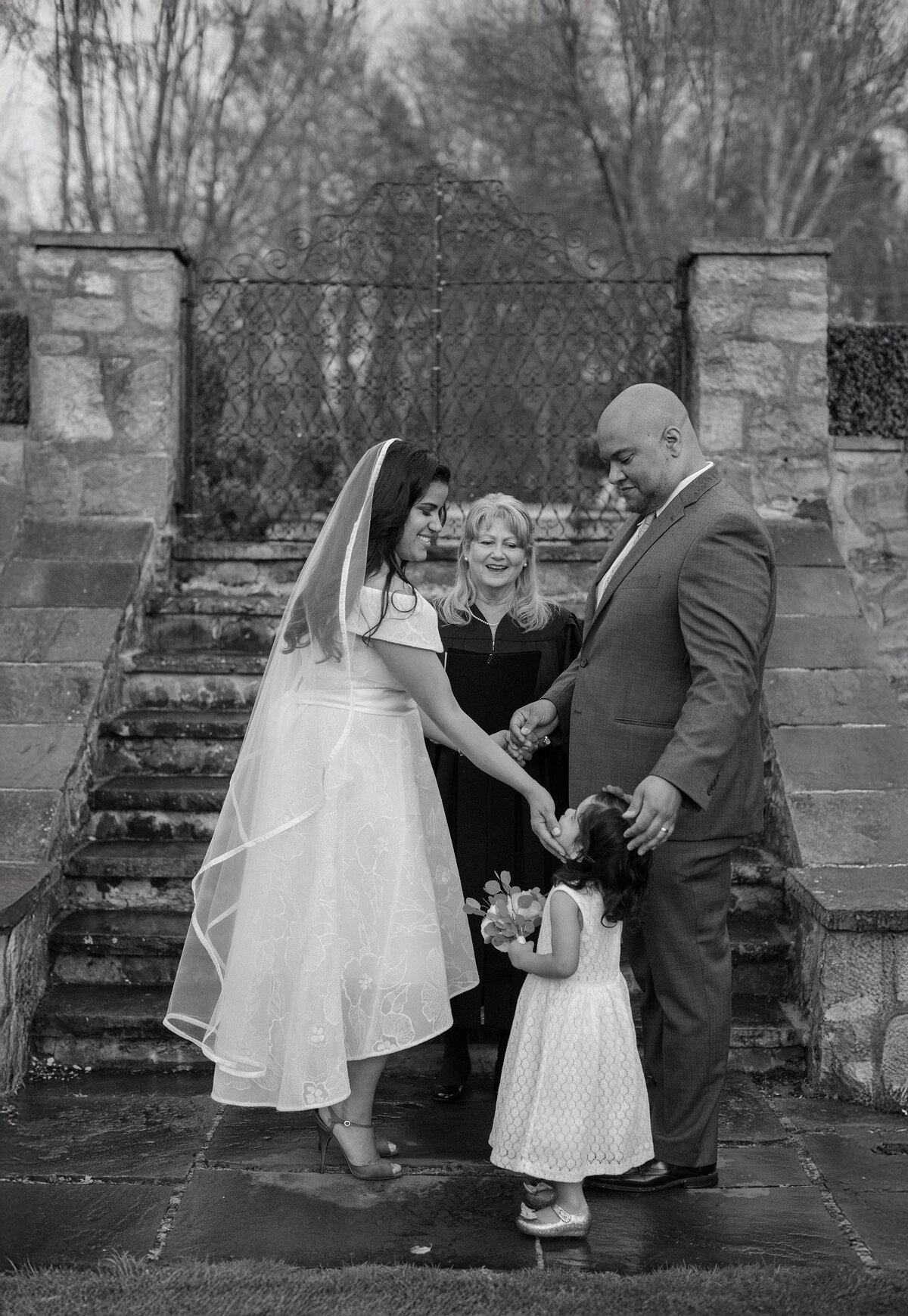 Bride and Groom place their hands on daughter's face during their wedding vows.