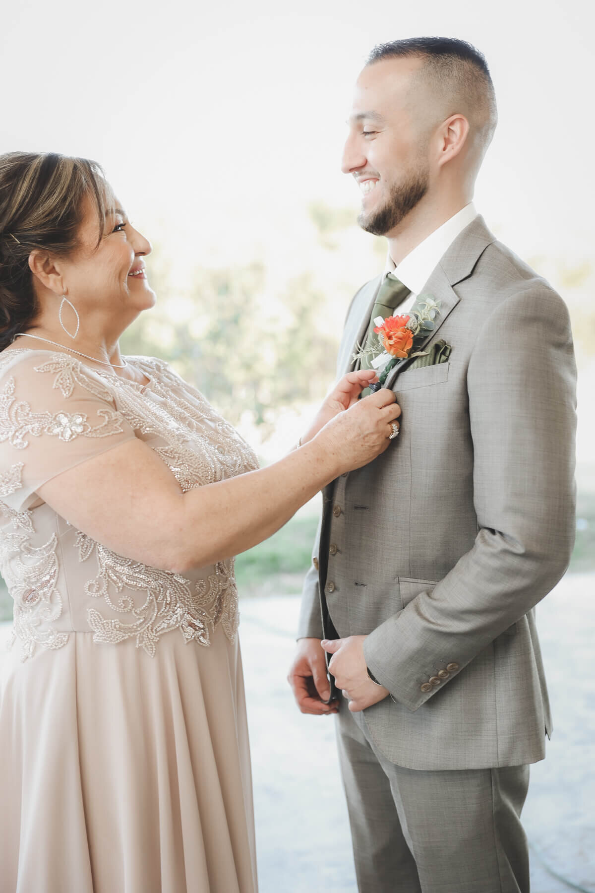 A groom's mother pins his flower on his jacket.