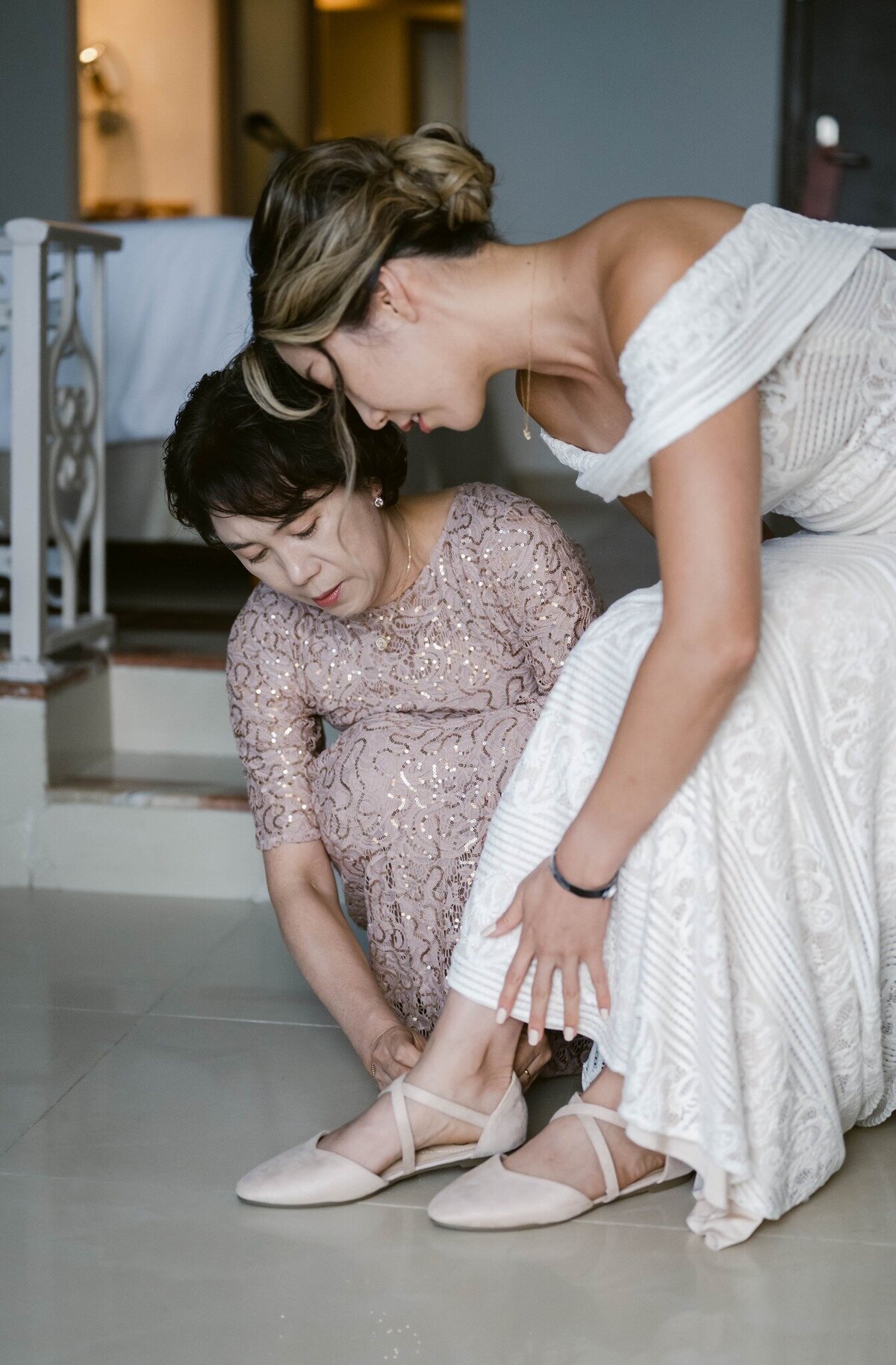 a mother helps her daughter put on her shoes at her Cancun wedding
