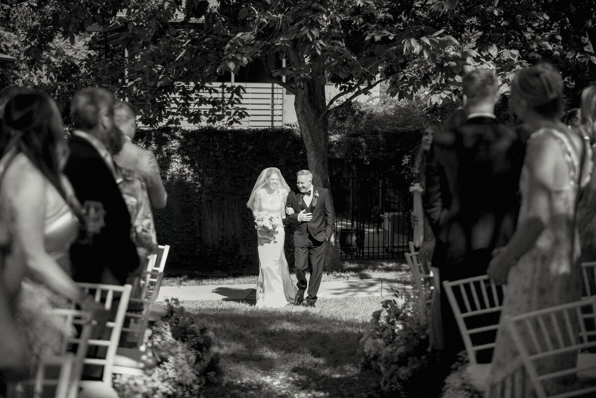 bride being walked down aisle by her father at outdoor wedding