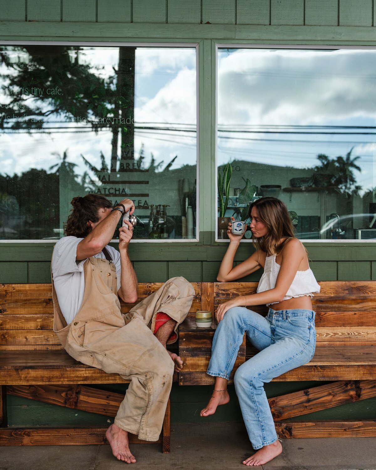 couple sitting on bench as man takes photo of woman