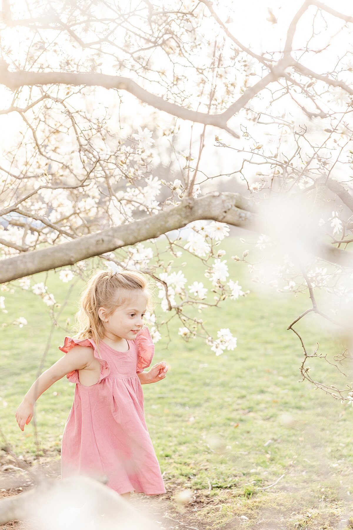 girl runs during spring maternity photo session in Wellesley Massachusetts with Sara Sniderman Photography