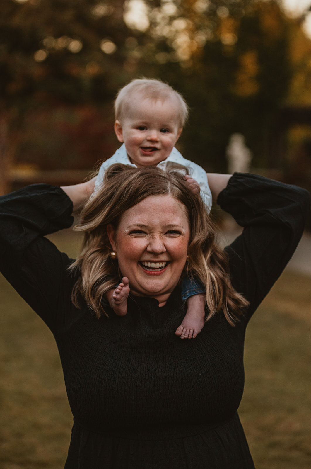 mom puts son on shoulders and smiles 