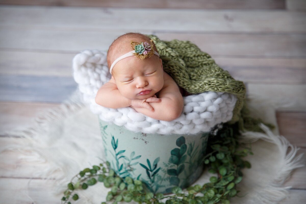 Picture of a newborn baby sleeping in a green bucket