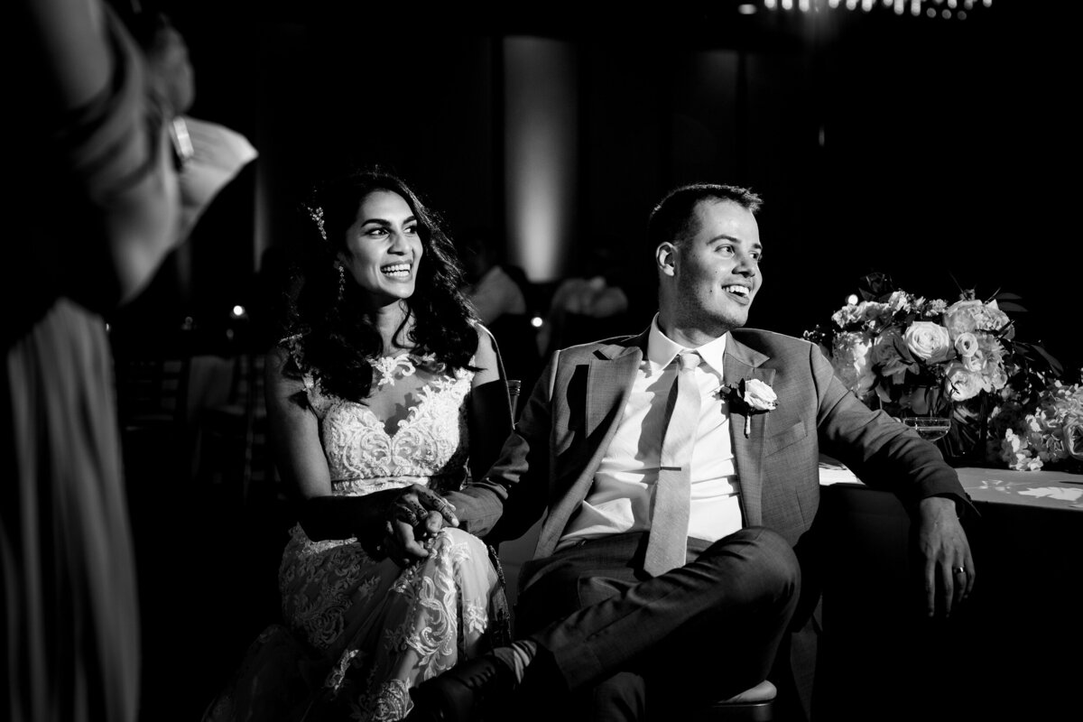 Wedding couple sitting and laughing during the toast of the best man during the reception at the Renaissance Hotel in Toledo Ohio