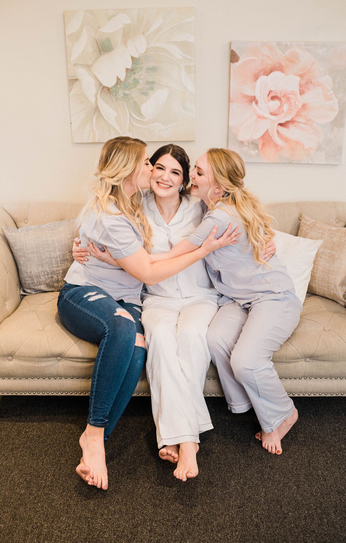 A bride sits on the couch with her bridesmaids in getting ready outfit
