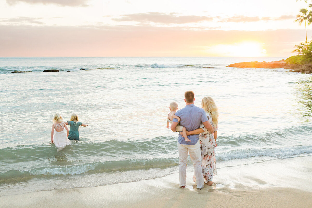 Photo of family on the beach, watching their children play in the ocean