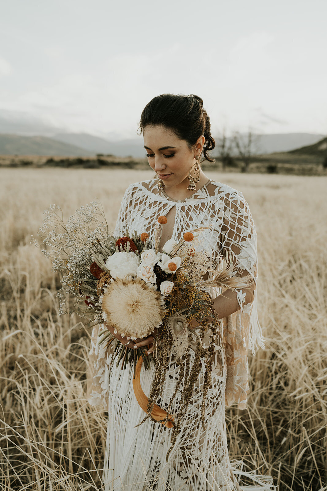 The Vase Floral Co - bride in south island new zealand field holds floral bouquet