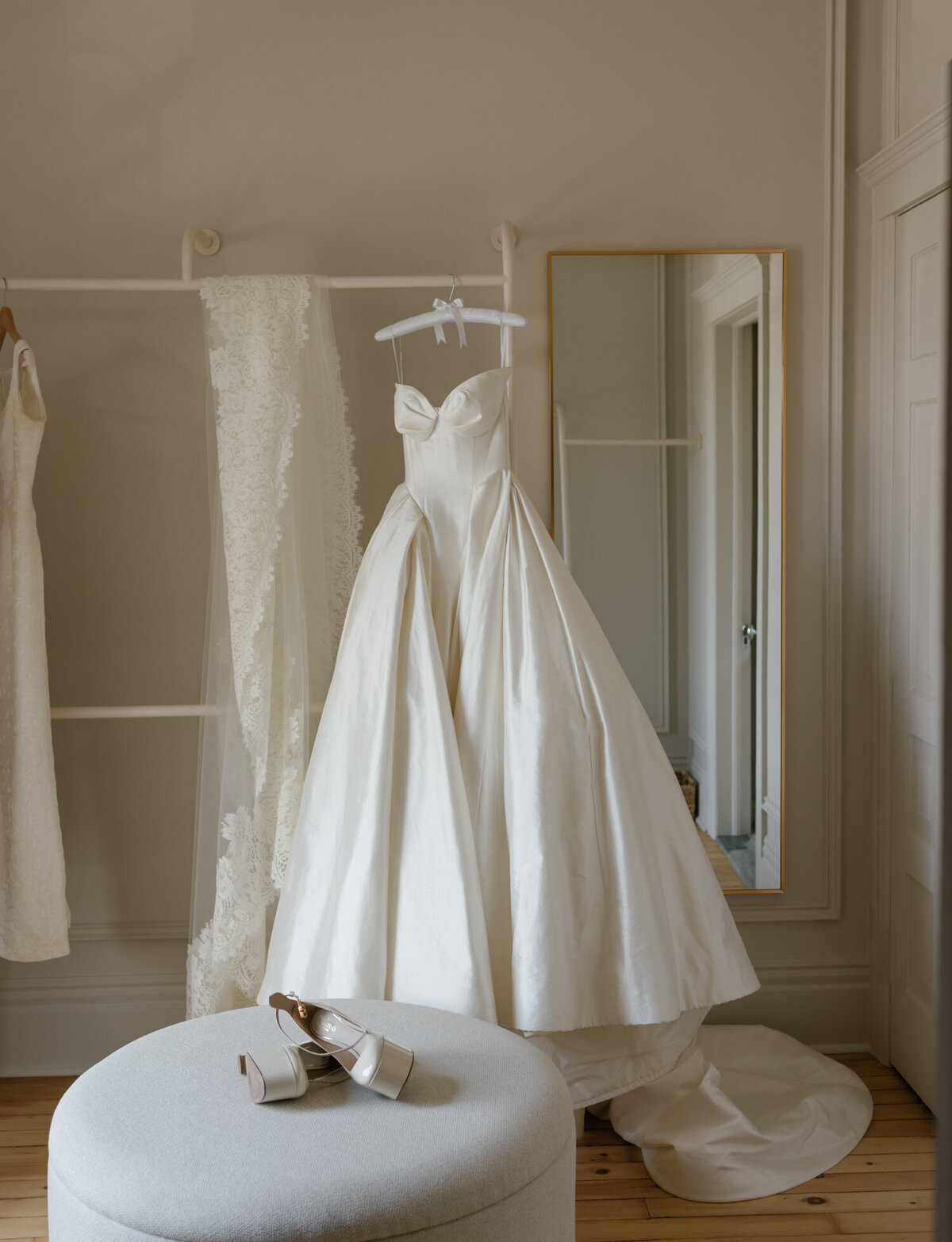 morning light filters into 1 Room Hotel in Detroit, a bride's silk Leah Dagloria ball gown hangs in the penthouse