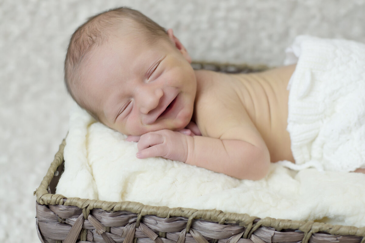 Newborn baby boy sleeping and smiling in basket
