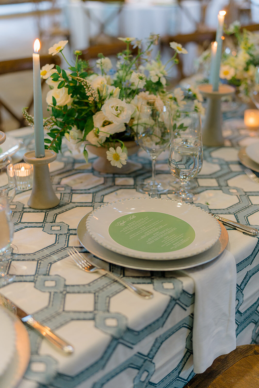 Wedding table setting with soft blue taper candle, petite floral centerpiece, and modern table number card at Old Edwards Inn reception.