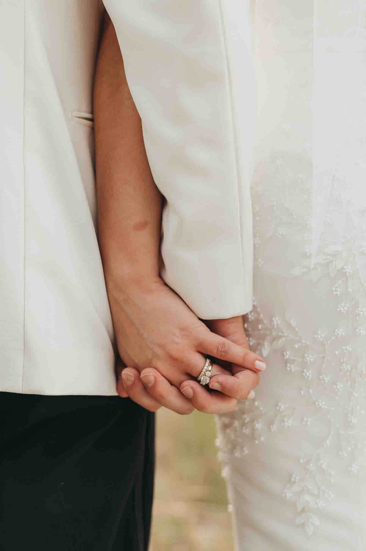bride and groom hold hands showcasing their wedding rings.