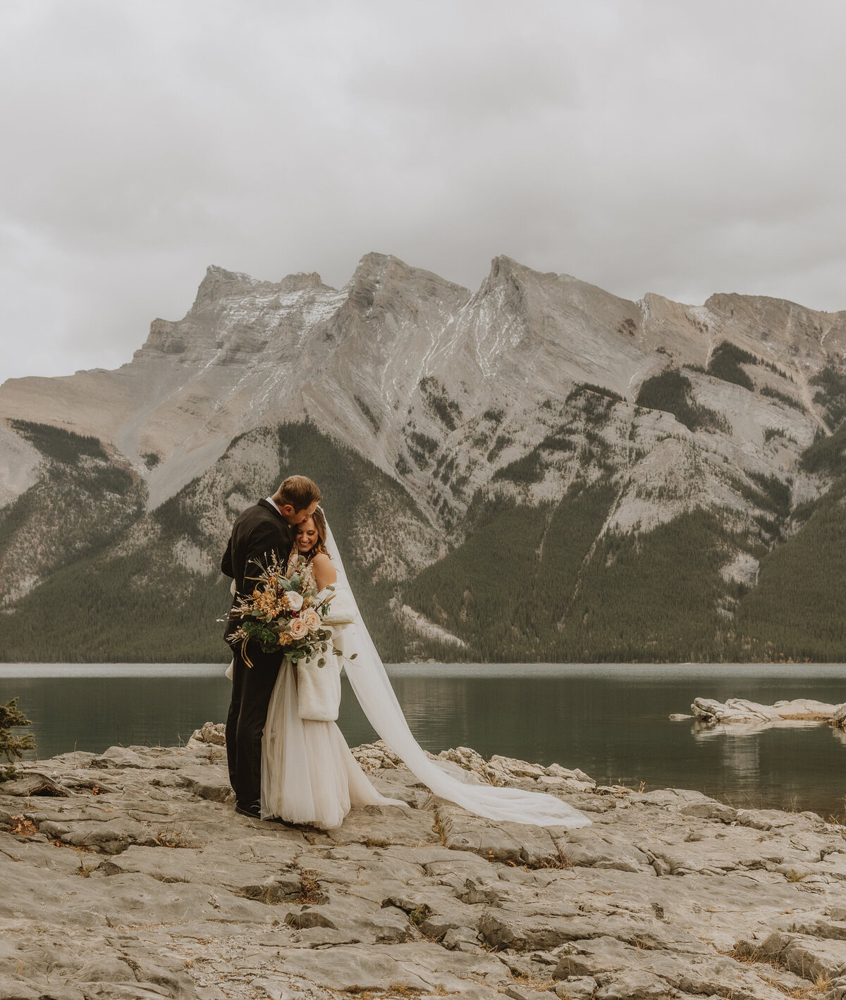 Couple snuggling by lake louise mountains in Banff, AB