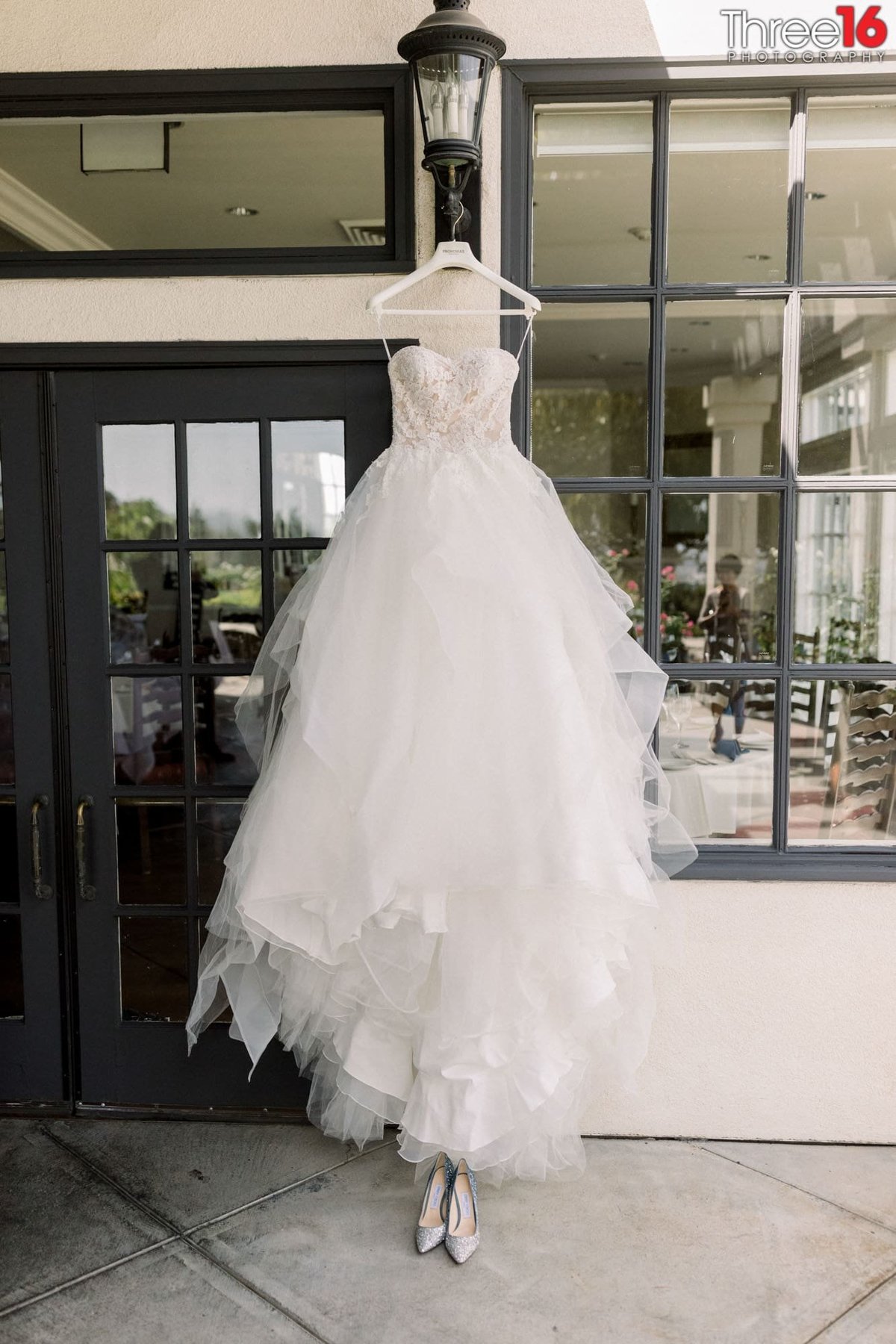 Bride's wedding dress hangs on display from a light fixture