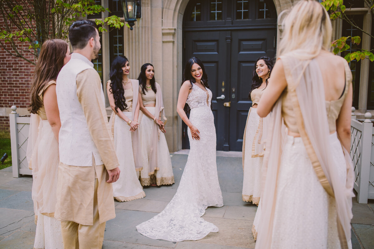 A bride showing off her white dress to the bridal party in front of the natirar mansion