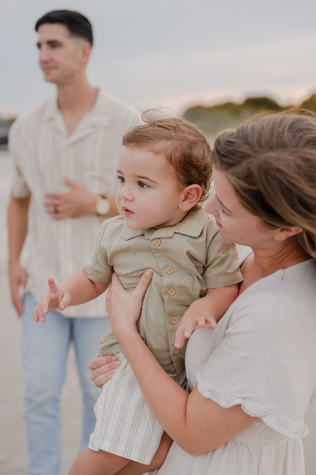 a family of three gazing into the distance on the beach