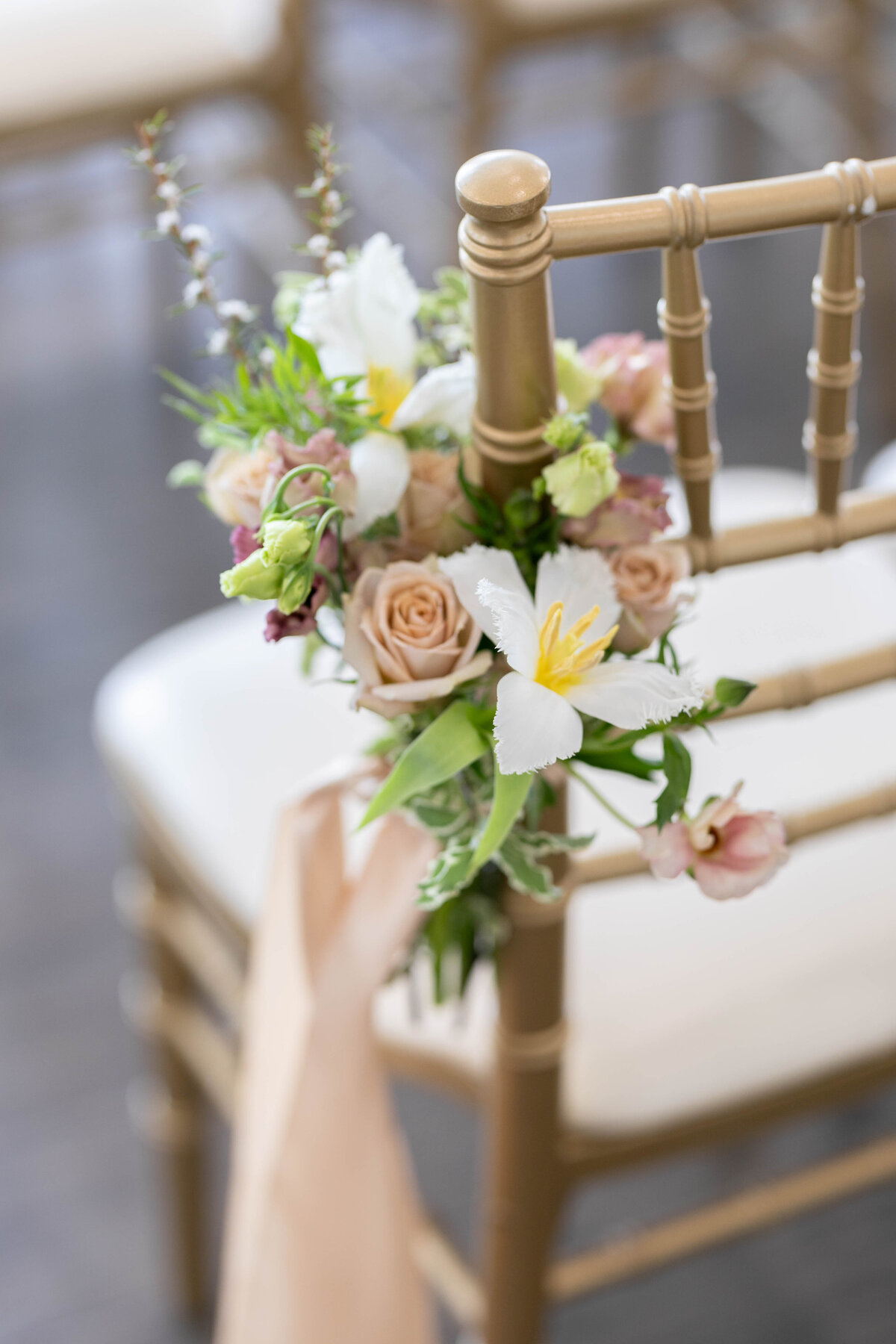 a bouquet of fresh flowers attached to a gold ceremony chair