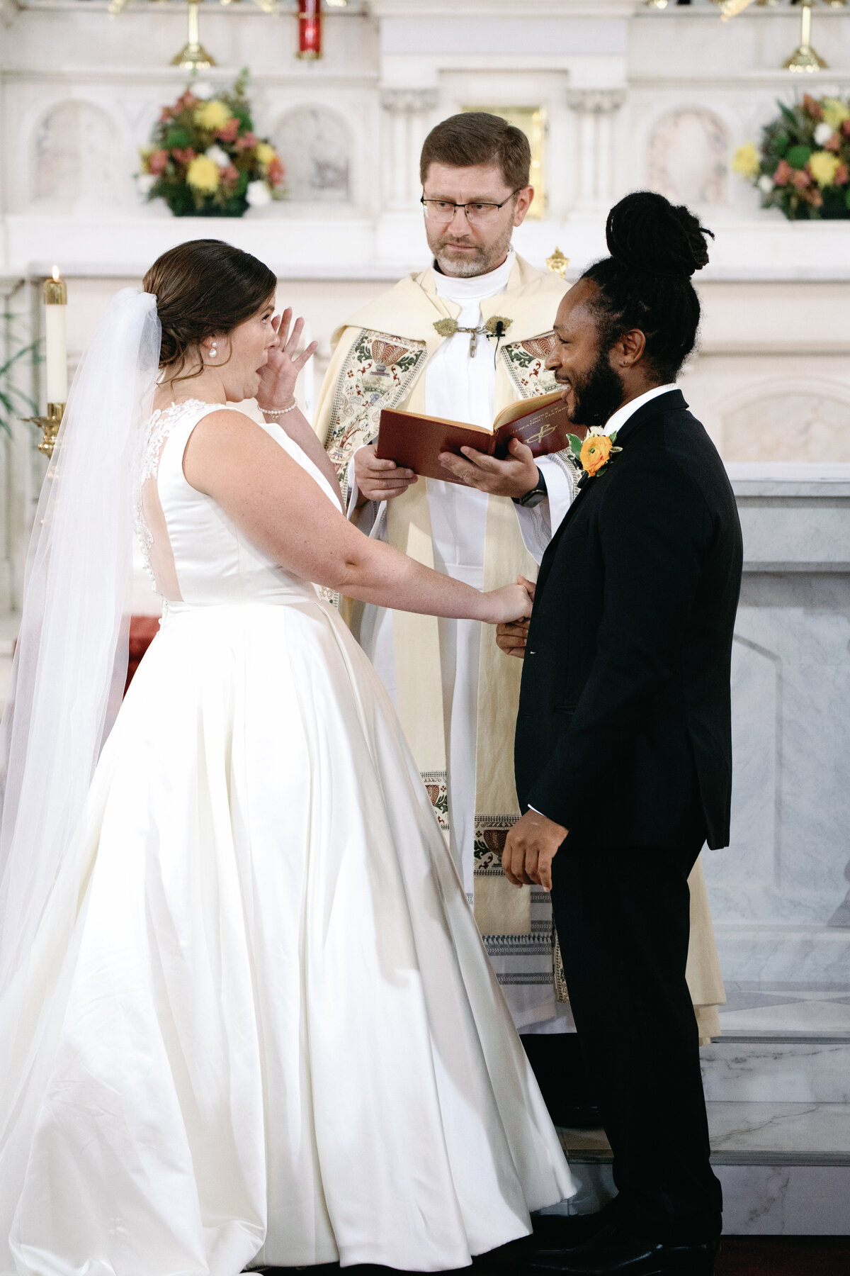 Bride and groom smiling as they exchange wedding rings during Catholic ceremony in Washington DC.