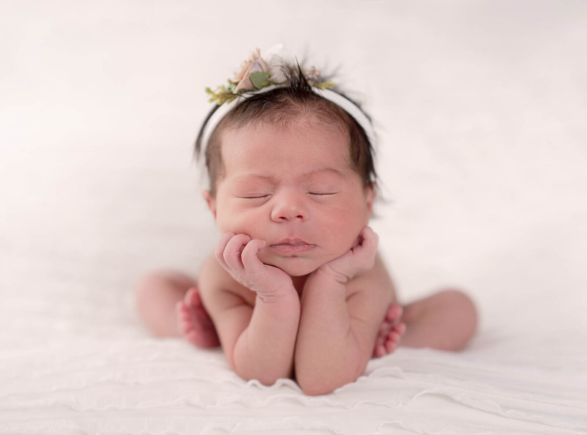 Newborn resting her head on her hands