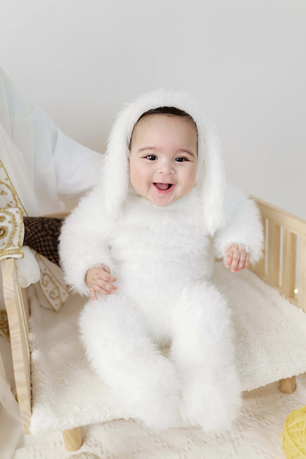 Baby boy in white bunny outfit on mini bed - whimsical indoor milestone session Maple Grove MN