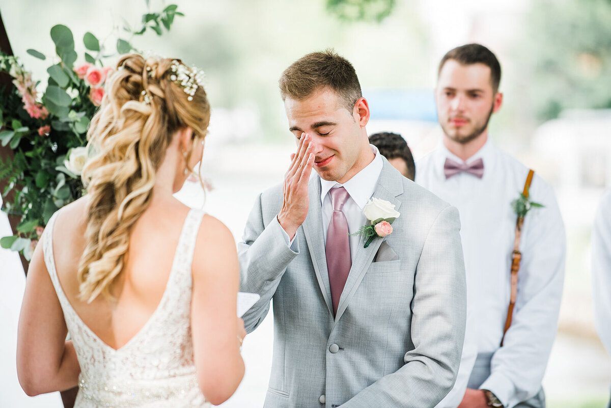 groom wiping tears during wedding ceremony at lake bomoseen lodge wedding