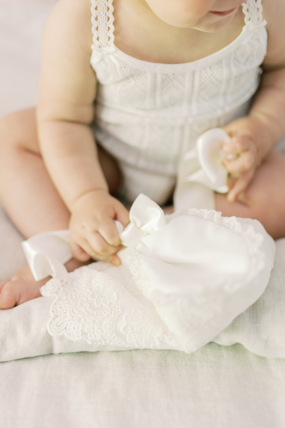 Delicate hands clutching a lace baptism bonnet—an intimate detail full of heritage and tenderness.