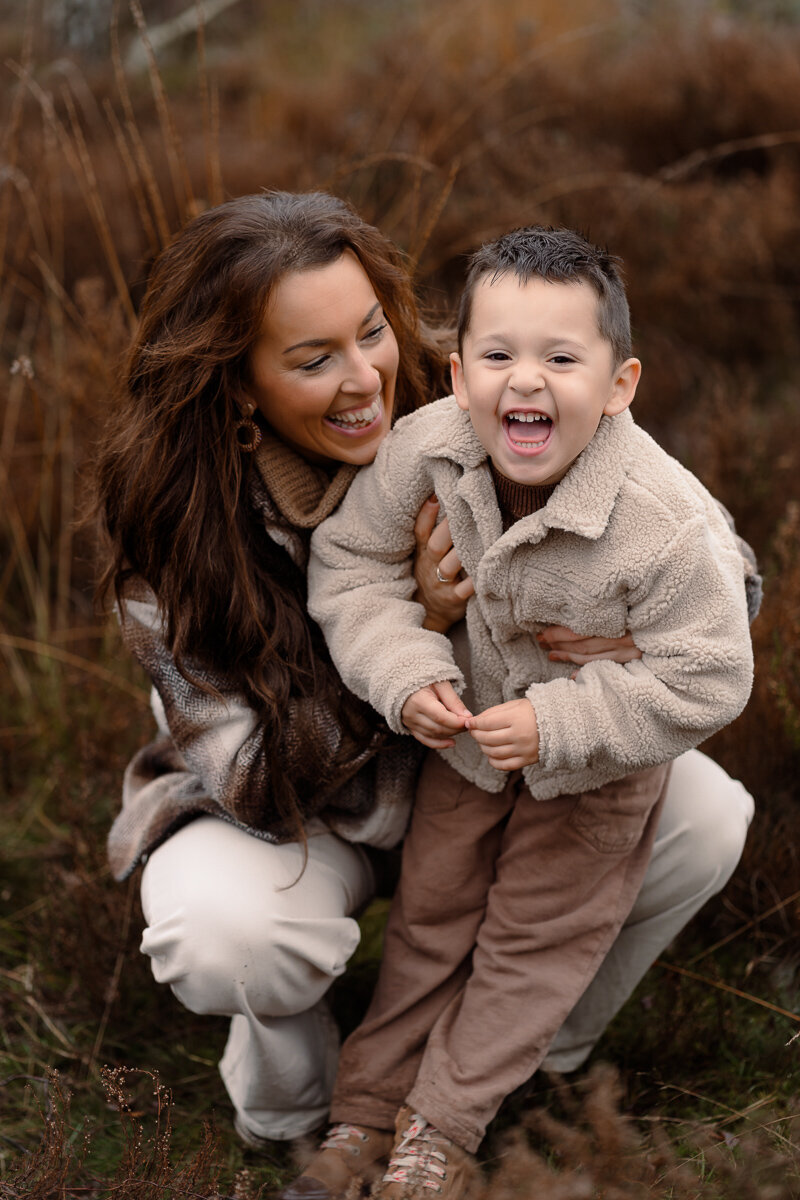 Moeder en zoon lachen met elkaar tijdens een shoot in de winter
