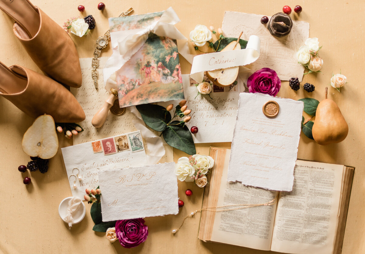 Romantic wedding stationery and details flatlay, styled by Wedding Stylist Rebekah Bronte, featuring vintage style wedding stationery and details, fruit, florals, and tones of honey, berry, green and brown. 