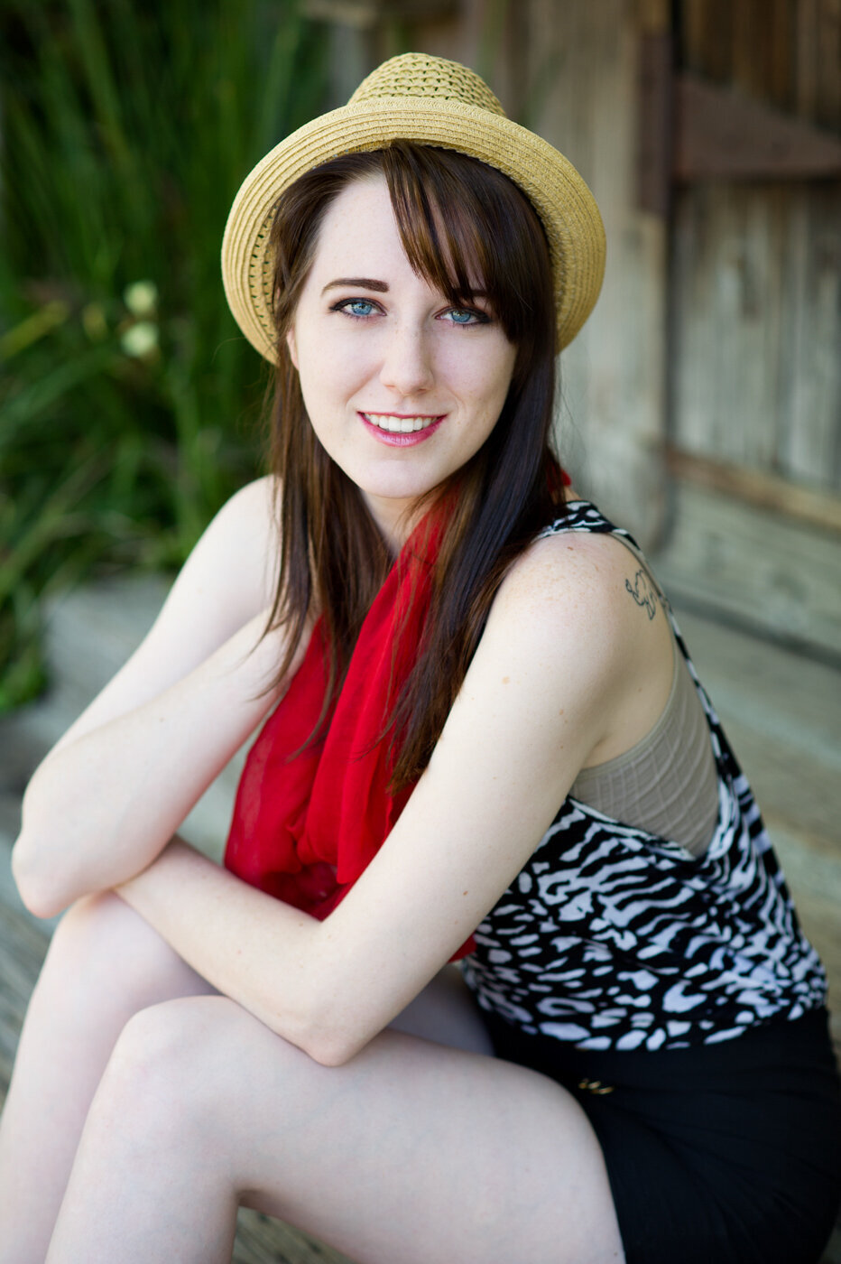 Commercial acting headshot of a smiling young woman wearing a red scarf and straw hat.