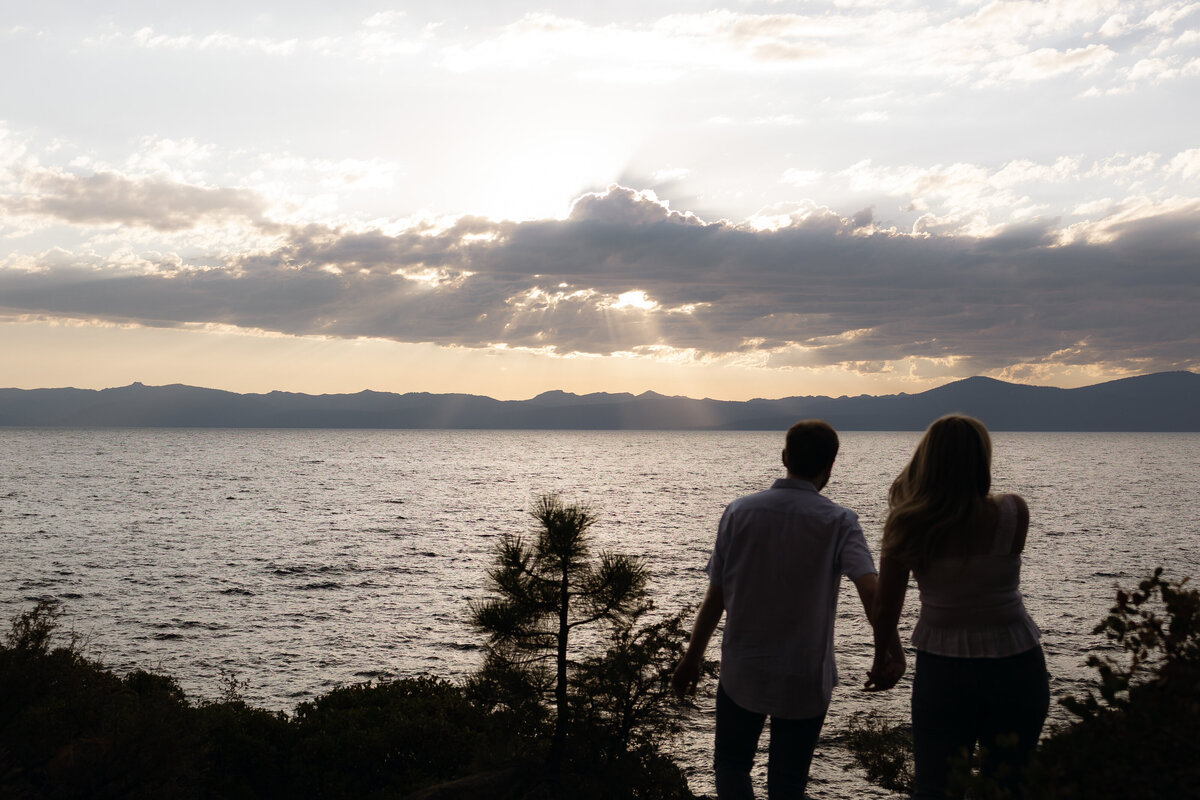 Cinematic wedding photo of a couple holding hands at sunset, overlooking Lake Tahoe, captured by documentary wedding photographers.