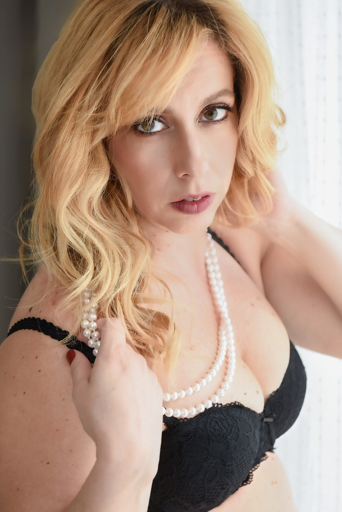 blonde woman with pearl necklace and black bra
