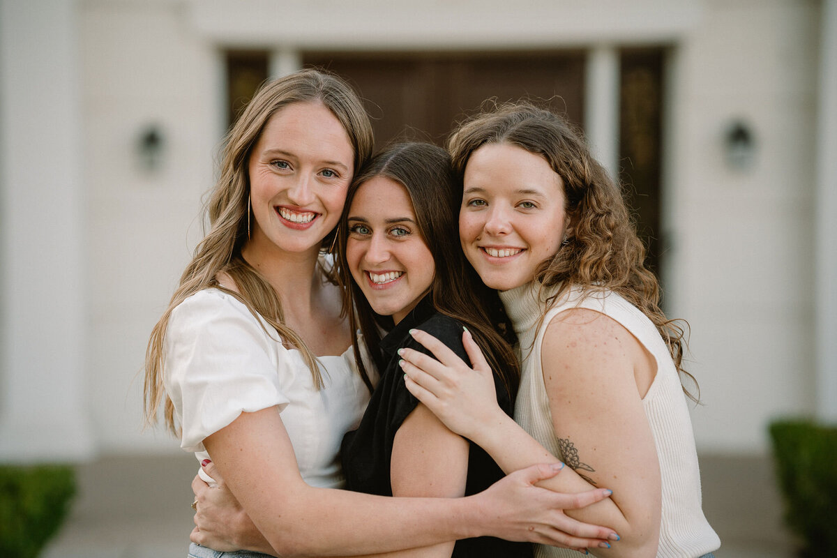 Three siblings smiling and hugging each other 