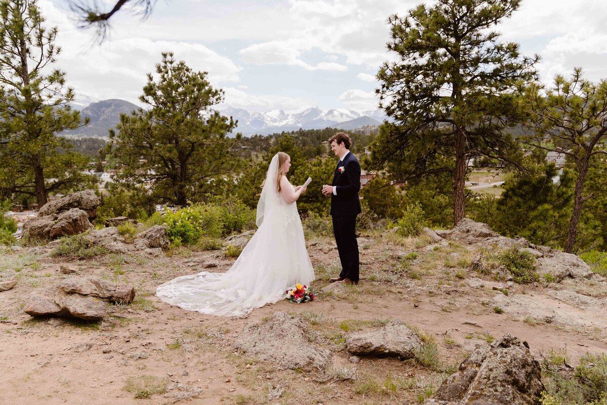 Estes Park Colorado elopement with couple sharing an emotional moment during vow reading with mountain backdrop.