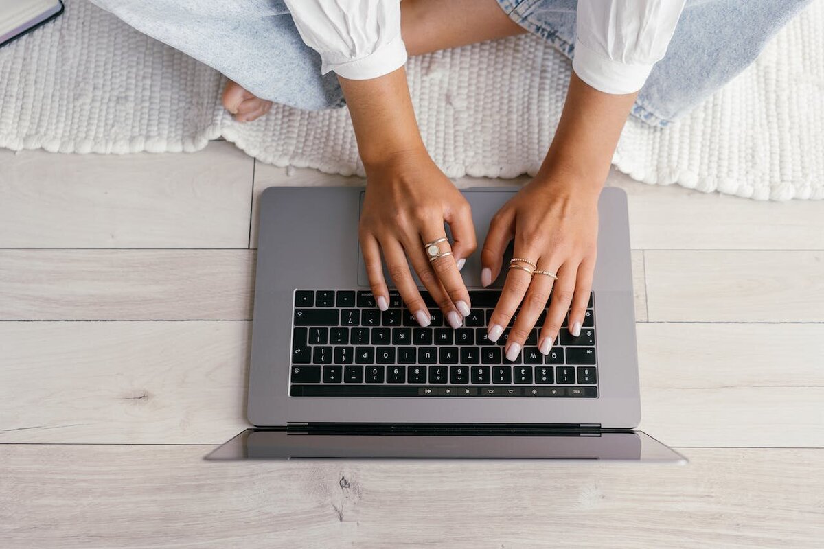 above view of a cross legged  woman's hands on a laptop