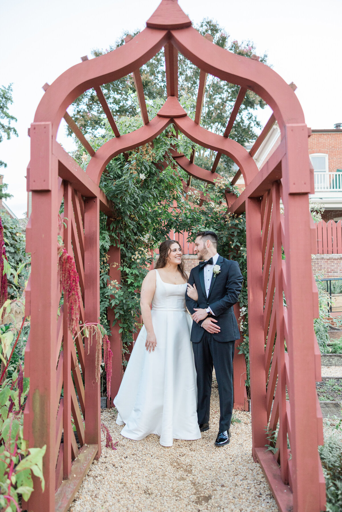 A wedding couple with their arms linked walking in a garden