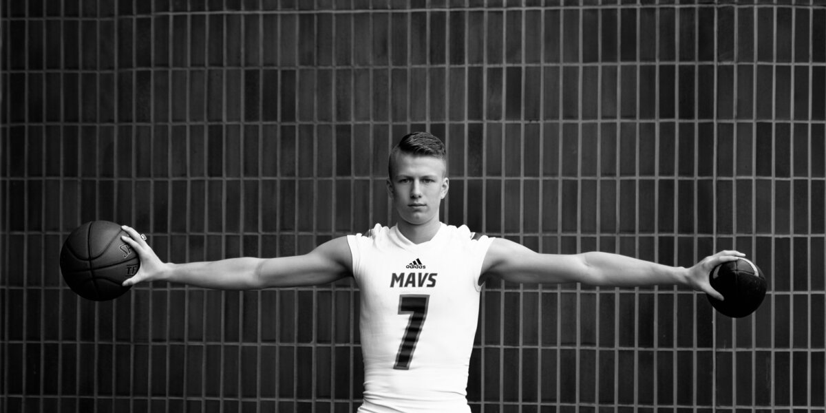 Senior boy holding a basketball ahnd a football in Downtown Boise.